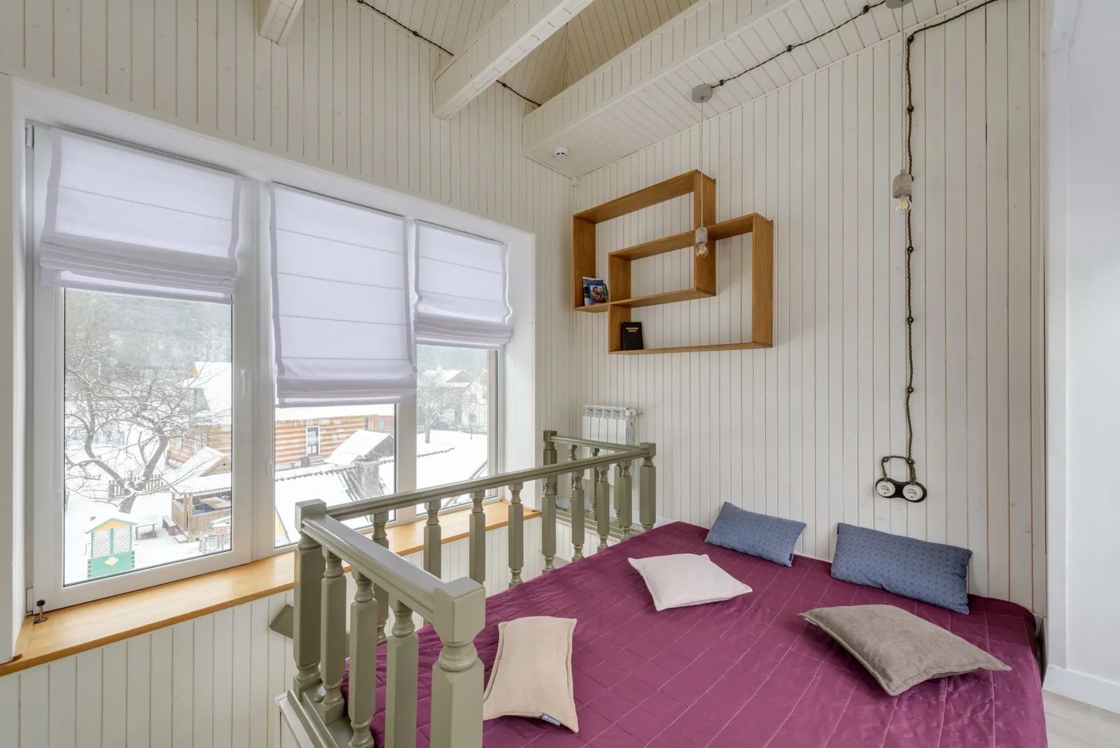 Helles Chalet-Schlafzimmer mit Holzbalken und Blick in den Schnee